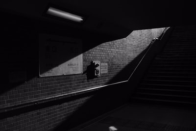 灰度照片黑夹克和裤子的男子站在楼梯
